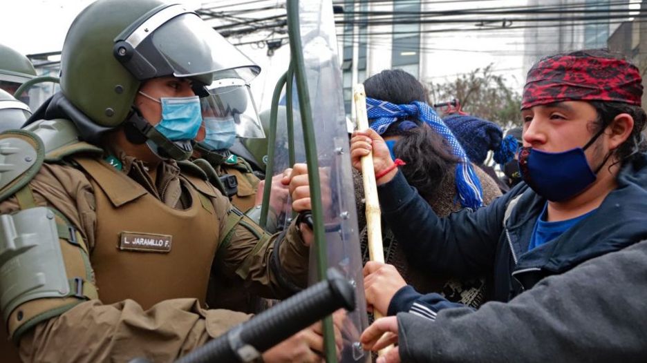 Mapuche en frente de miembros de seguridad chilenos.