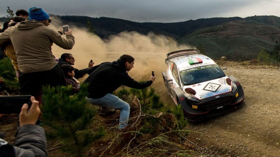 People take pictures of a rally car