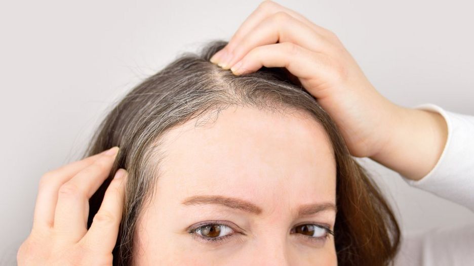 Woman looking at grey hairs appearing