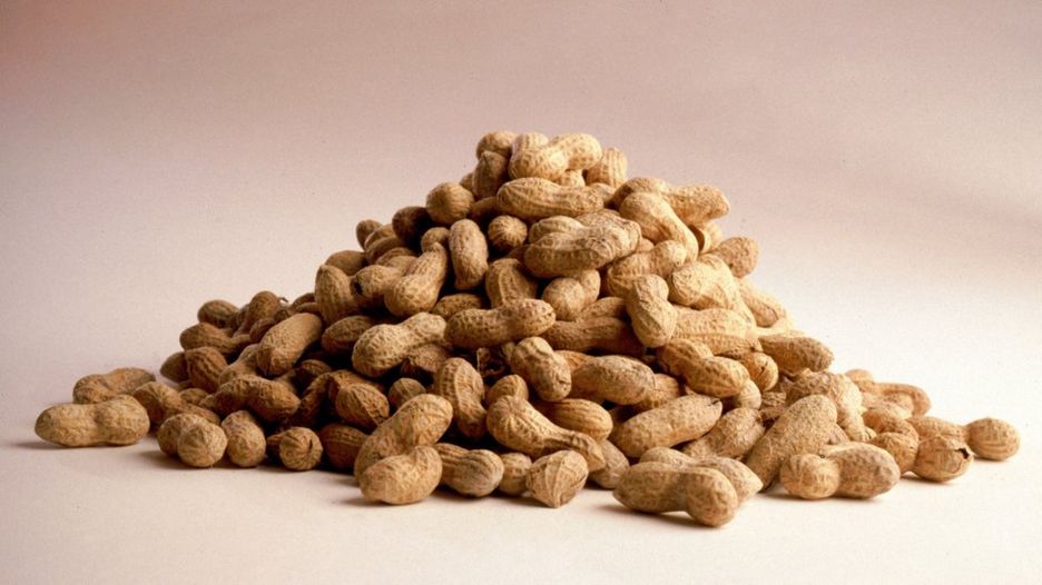 A photo of a mound of peanuts still in their shells