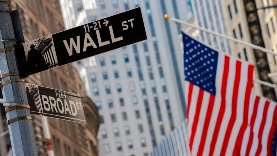 Placa de rua de Wall Street com bandeira americana ao lado