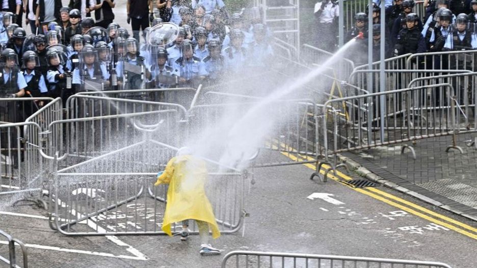 Police officers spray a lone protester near the government headquarters in Hong Kong on June 12, 2019