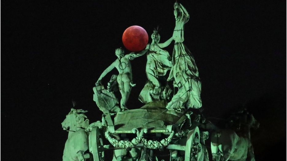 The moon is seen beside a quadriga on the top of the Cinquantenaire arch during a total lunar eclipse, known as the "Super Blood Wolf Moon", in Brussels