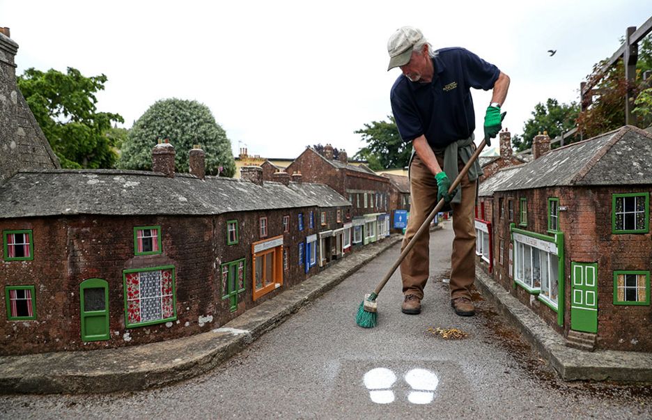 A man sweeps the ground in the middle of a street in a model town