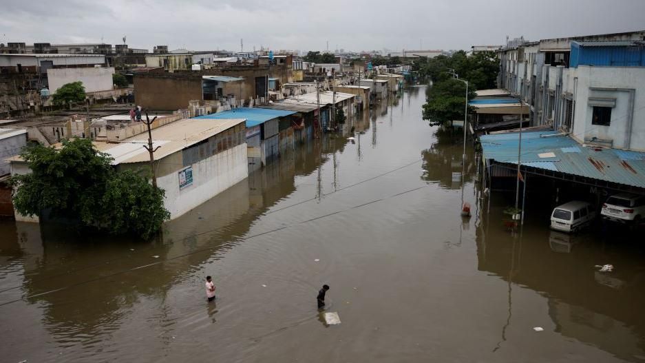 People cross a flooded street after heavy rains in Ahmedabad, India, August 28, 2024