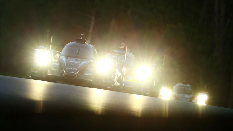 Three cars race at night at Le Mans