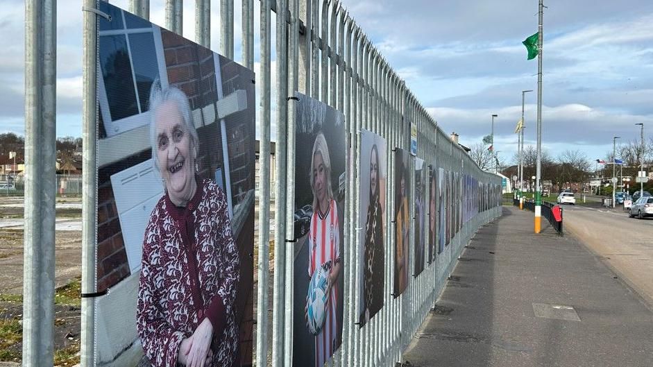 Portraits of women hang from a steel fence on a street in Derry's Bogside