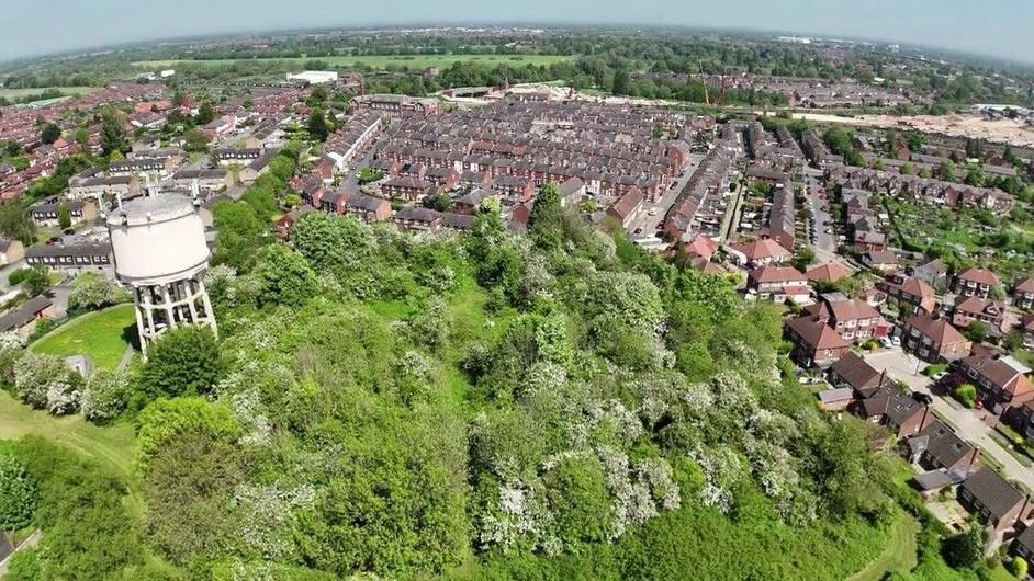 An aerial view of Severus Hill including a white water tower, the green of the natural land and the surrounding housing estate 