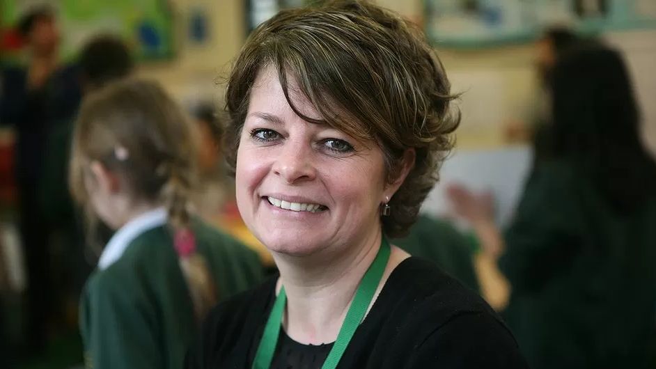 Ruth Perry, a woman with short brown hair wearing a green lanyard