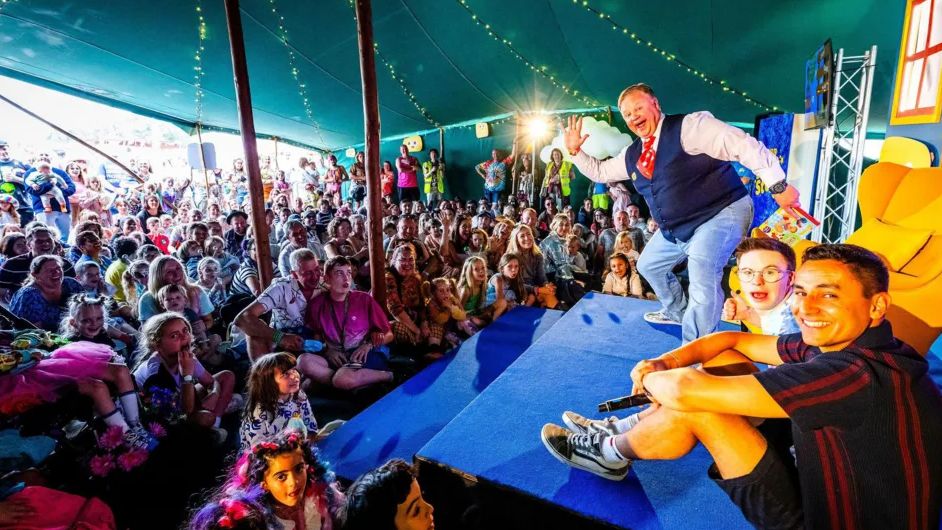 Crowds of adults and children gather in a tent at the festival to see Mr Tumble appear