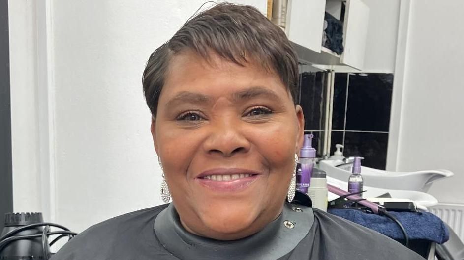 Dionne Litchmore smiling as she sits in hairdressing chair