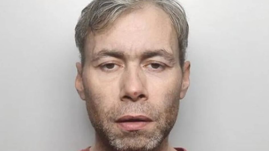 Liam Jones' mugshot. A middle aged man, with a greying beard and grey hair in front of a grey background