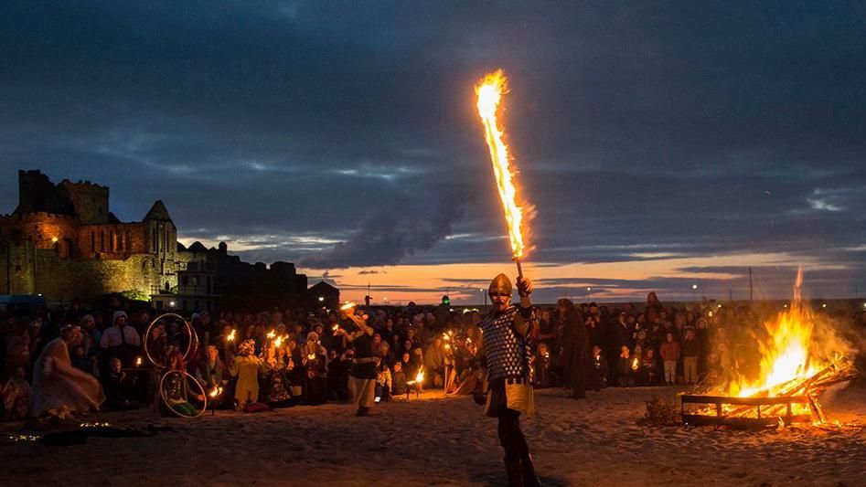 A crowd on Peel Beach as people perform by fire pits