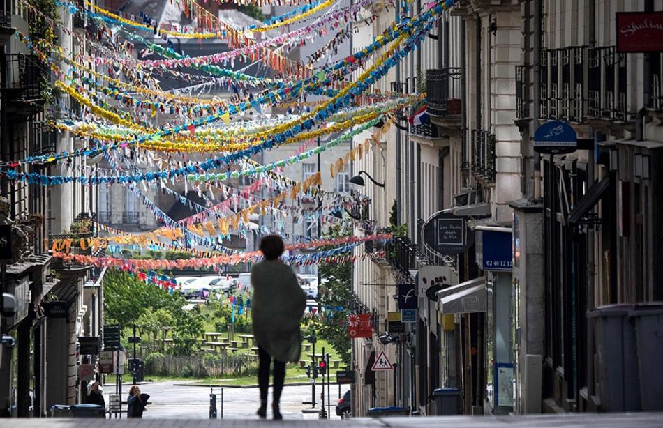 A woman walks down a street decorated by dozens of handmade garlands