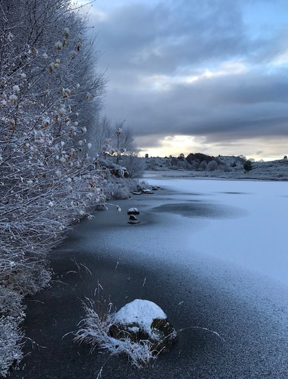 A frozen river with snow on top