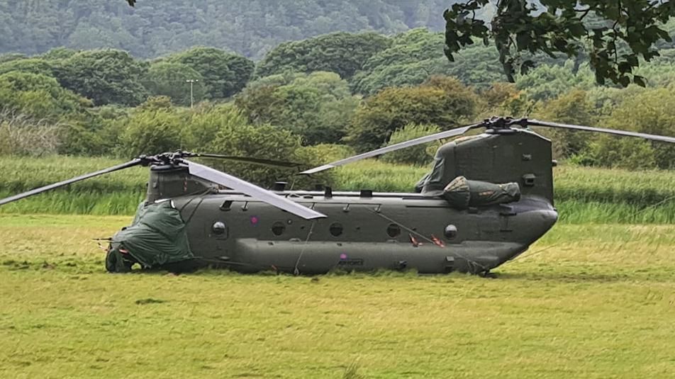 Chinook helicopter on field where its undercarriage has sunken into mud