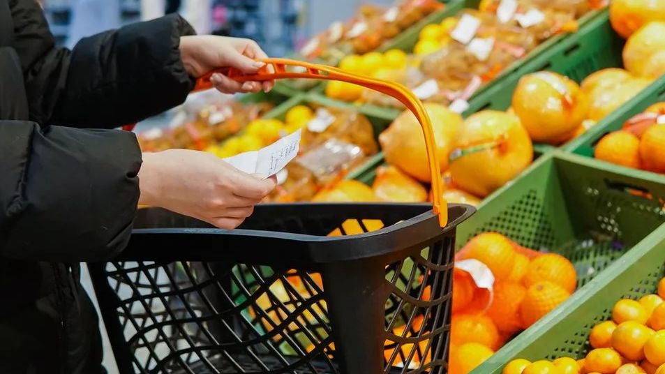 Woman carrying basket of fruit in a shop