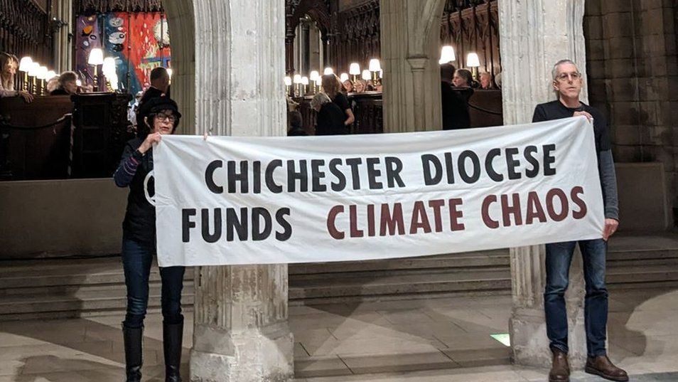 Climate protesters holding a banner that reads: Chichester Diocese funds climate chaos