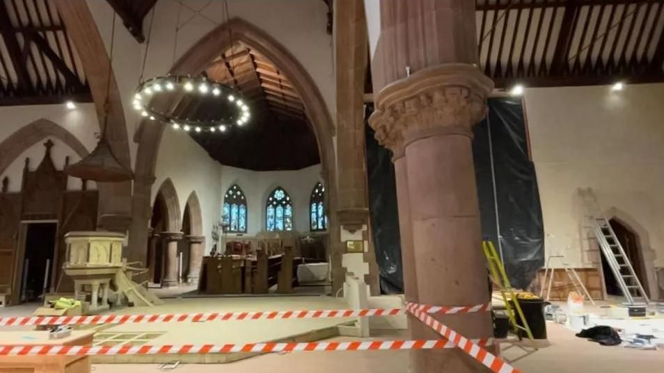 The interior of the cathedral while works were underway. Red and white tape cordons off some sections and paint pots, ladders and tools can also be seen.