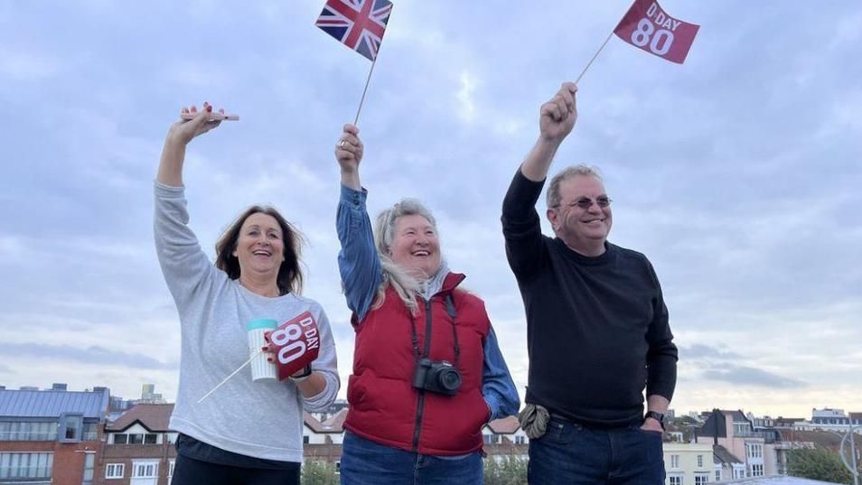Three people on the Round Tower, Portsmouth waving flags