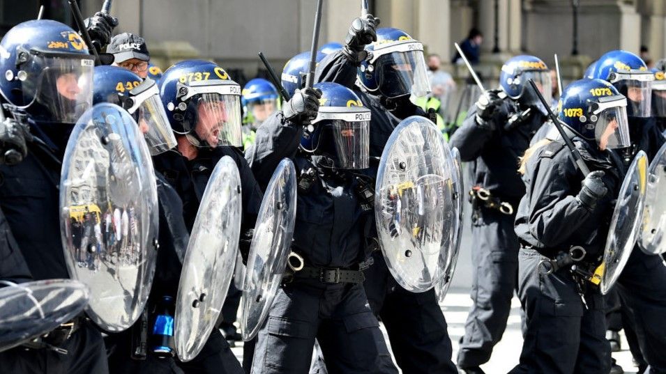 Police officers in riot gear with batons during protests in Liverpool on 3 August