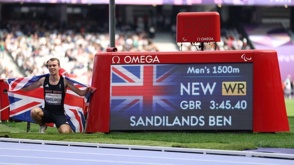 Ben Sandilands celebrates with a Union Jack draped over his shoulders