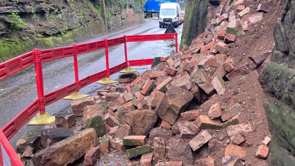 A pile of bricks next to a collapsed wall in Town Street, Bramcote, with a red barrier surrounding the rubble