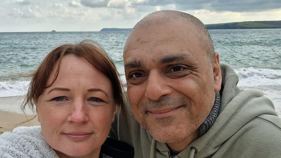 Simone and George smiling in front of the sea