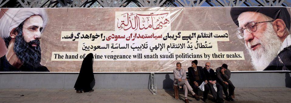 People sit in from of a banner with the pictures of prominent Shia cleric Sheikh Nimr al-Nimr and Iran's Supreme Leader Ayatollah Ali Khamenei