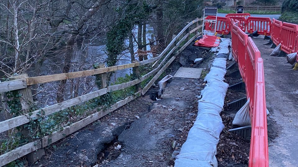 A wooden fence partially collapsed into the river