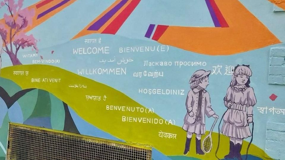 A section of the mural with the word 'welcome' in many languages