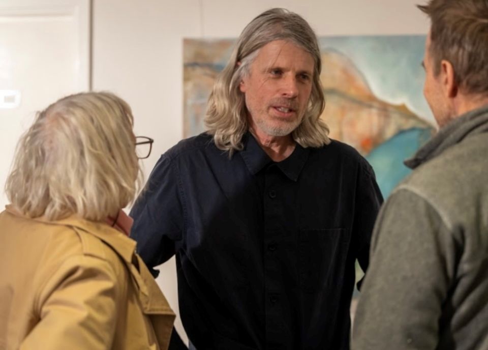 Jonny Church talking to two members of the public with a large painting behind him