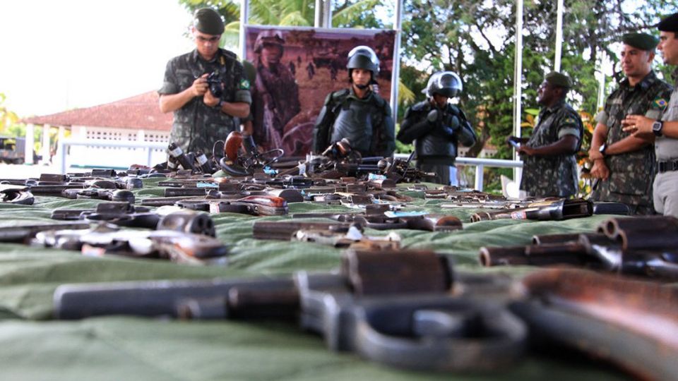 Soldados observam armas em mesa