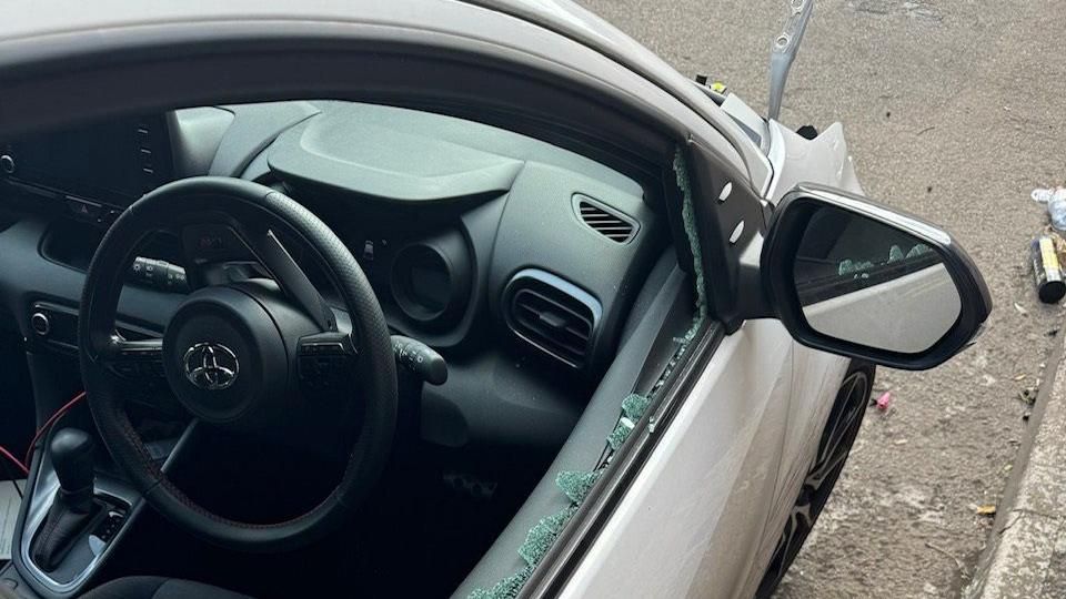 Broken glass around frame of window of white car
