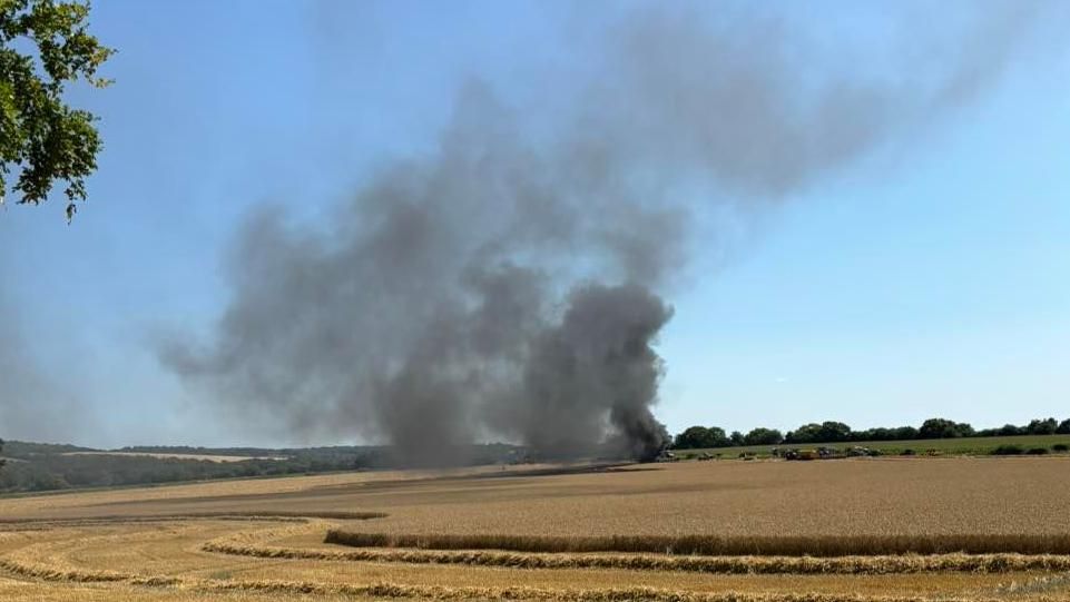 thick, black smoke rising from a field in the distance