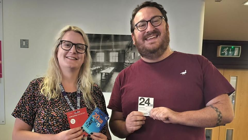 Ellen Clayton and Thomas Hollyer, of Suffolk Libraries, smiling and holding some of the Sim cards available through the scheme