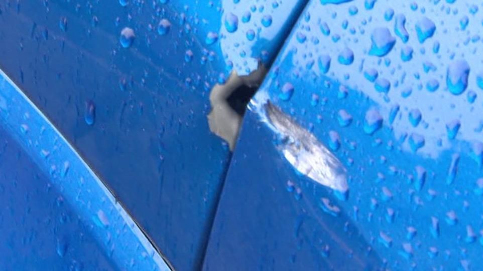 Close-up of an alleged bullet-hole in the side of a blue rain-covered car