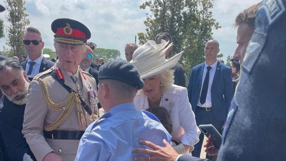 Toby walks towards King Charles III, with President Emmanuel Macron guiding him with a hand on his back