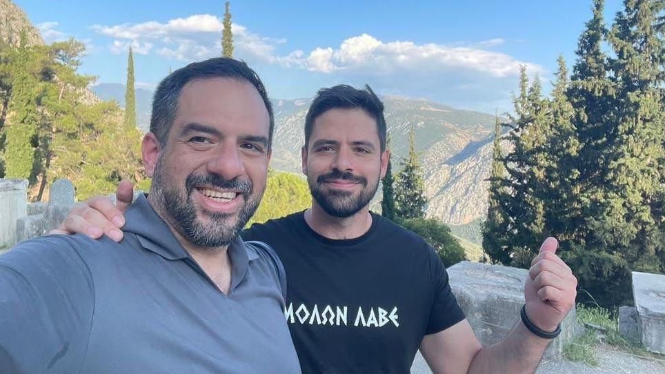 Two men take a selfie on top of a mountain