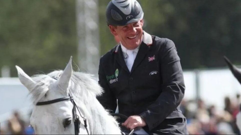 Showjumper Tim Stockdale on horseback, smiling as he takes part in a showjumping event