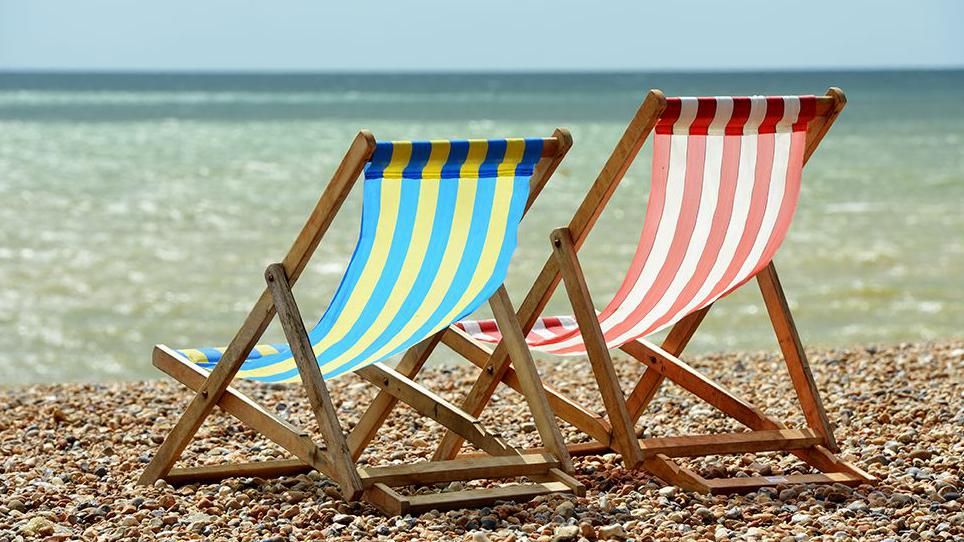 Two empty deckchairs on a beach