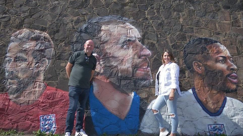 A couple standing in front of a mural wall