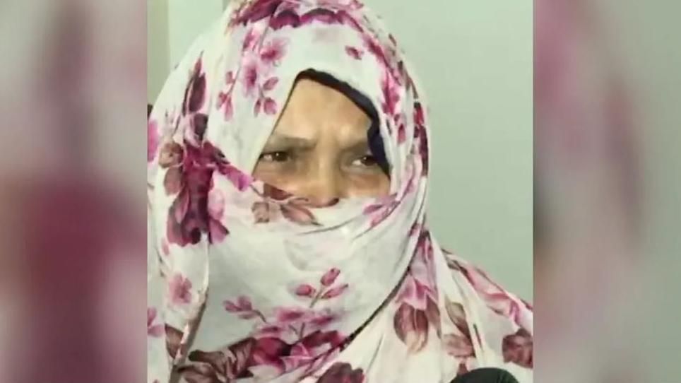 Woman wearing a face and head covering depicting flowers speaks to a camera