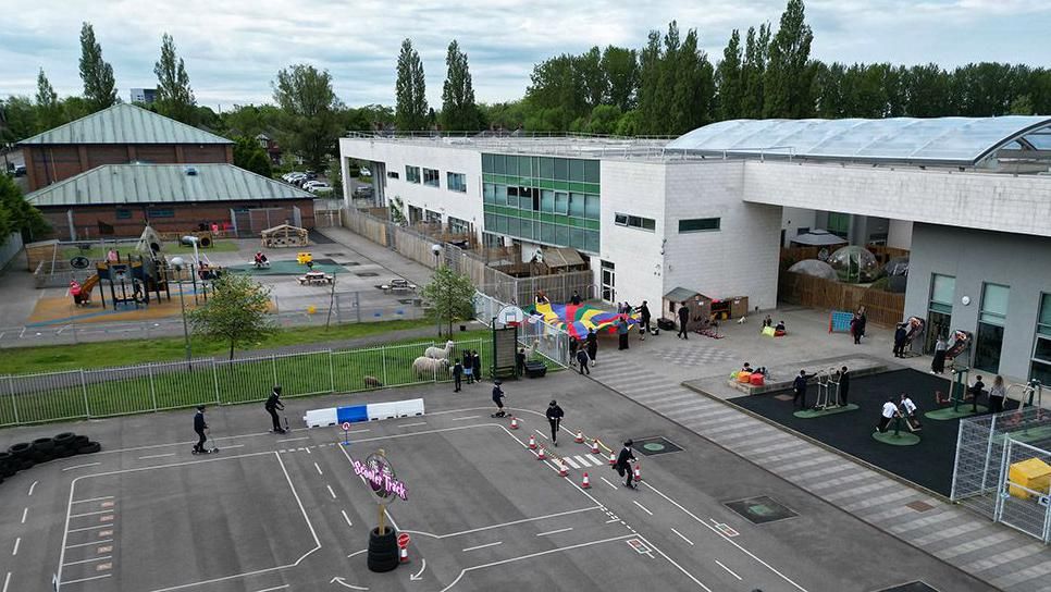 External view of Grange School buildings and outdoor facilities such as a track where pupils are riding scooters with helmets on
