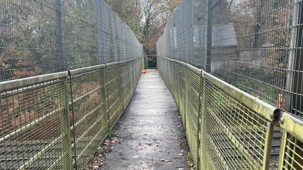 A users view of an old and slightly wonky footbridge above a trainline