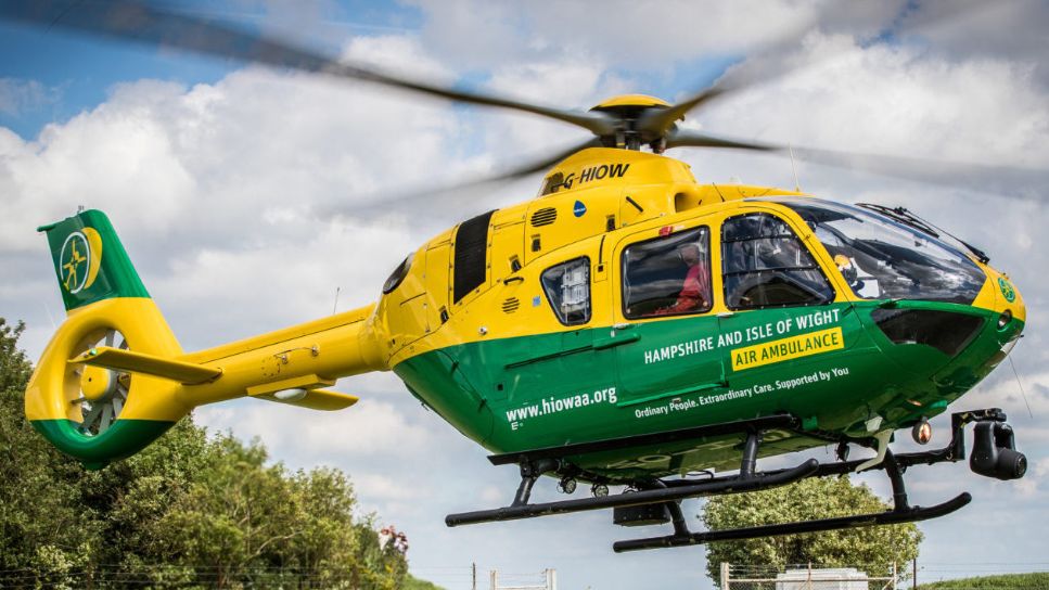 A green and yellow helicopter air ambulance in mid-air