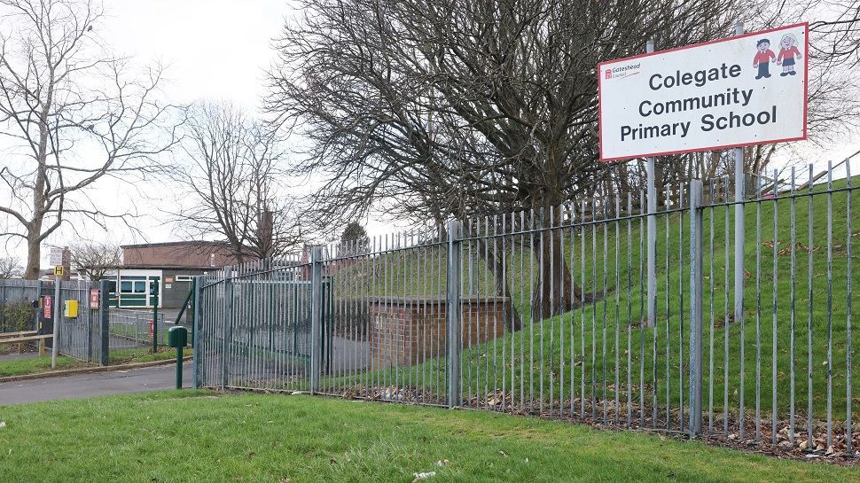 The outside of Colegate School surrounded by metal fencing and fields.