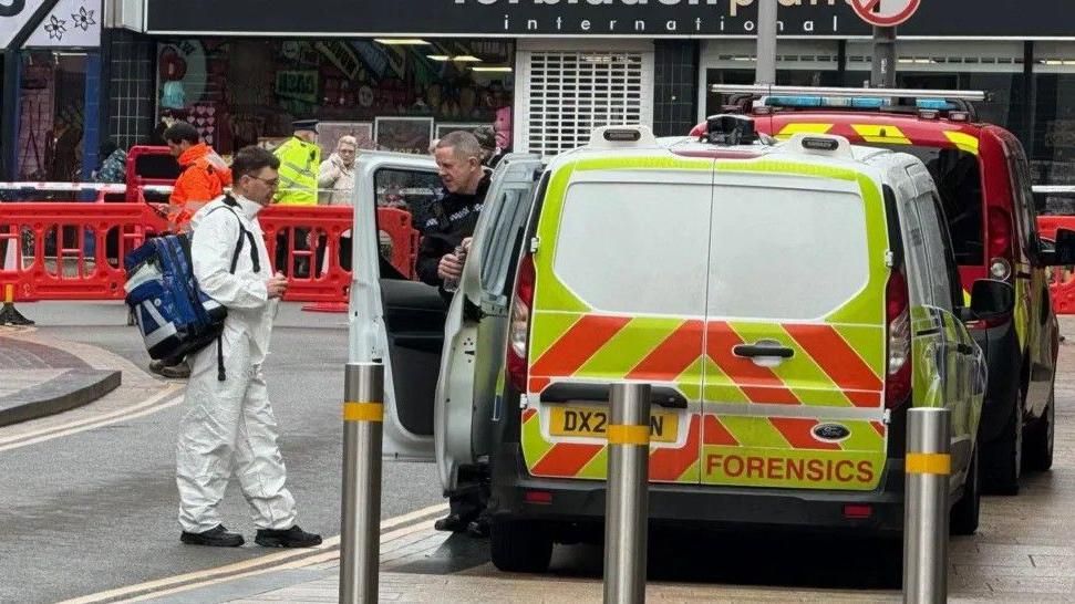 Forensic officer and police vehicles at the scene