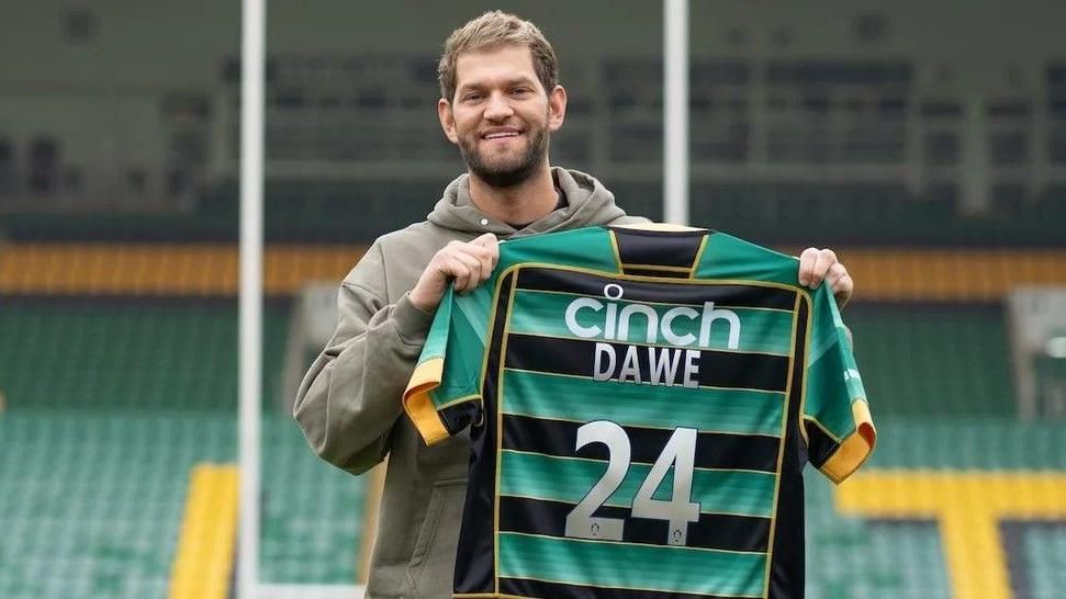 Nathan Dawe with short brown hair and beard holding a Saints shirt with his name on the back