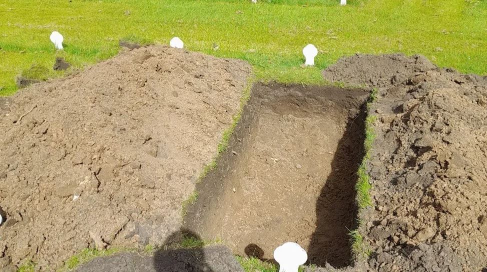 A shallow grave with piles of earth either side